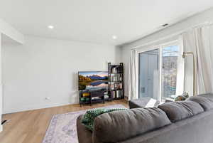 Living room with light wood-style flooring and recessed lighting