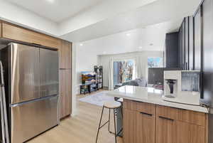 Kitchen featuring freestanding refrigerator, a peninsula, light wood finished floors, a breakfast bar area, and open floor plan
