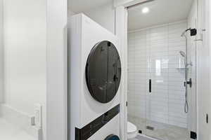Full bath with a stall shower, stacked washer / dryer, and recessed lighting