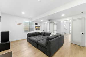 Living area with light wood finished floors and recessed lighting