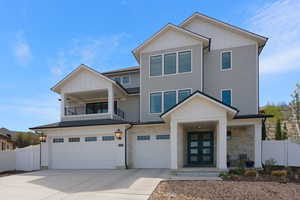 View of front of home with board and batten siding, stone siding, an attached garage, and concrete driveway