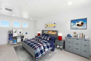 Virtually staged Bedroom with light colored carpet and recessed lighting