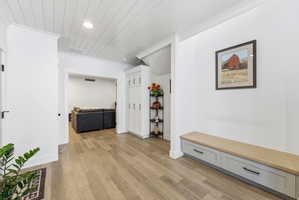 Corridor featuring light wood-style floors, storage lockers, crown molding, recessed lighting, and wood ceiling