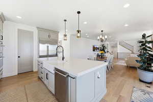 Kitchen with light wood-style floors, open floor plan, a center island with sink, stainless steel appliances, and pendant lighting