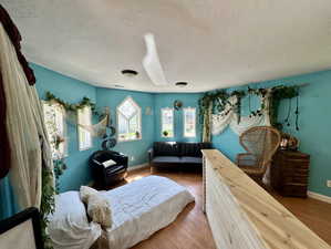 Bedroom with a textured ceiling and wood finished floors
