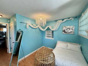 Bedroom featuring suspended lighting, wood finished floors, a closet, and a textured ceiling