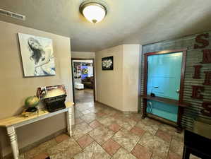 Hallway with a textured ceiling and stone tile floors