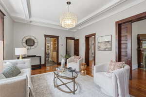 Living room featuring suspended lighting, wood finished floors, and ornamental molding