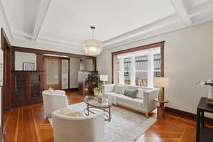 Living area with wood-type flooring, hanging lights, and coffered ceiling