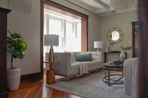 Living area with hardwood / wood-style floors, a chandelier, and coffered ceiling