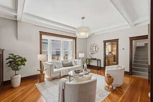 Living room with beam ceiling, wood-type flooring, and suspended lighting