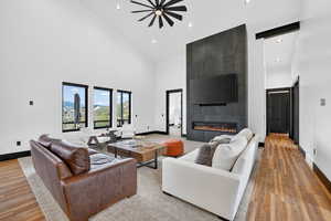 Living room with a fireplace, wood finished floors, ceiling fan, recessed lighting, and lofted ceiling