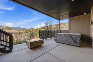 View of patio / terrace featuring a mountain view, an outdoor fire pit, and a hot tub