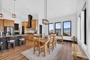 Dining room with light wood-style floors, hanging lights, a mountain view, and lofted ceiling