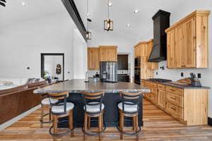 Kitchen featuring a kitchen island with sink, a kitchen bar, light wood-type flooring, open floor plan, and lofted ceiling