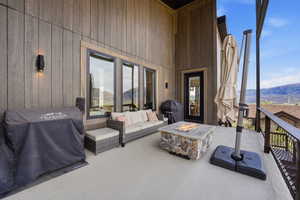 Wooden terrace with a mountain view, area for grilling, an outdoor living space with a fire pit, and a patio