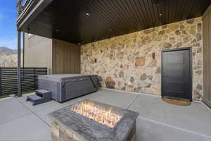 View of patio with a hot tub, a mountain view, and an outdoor fire pit