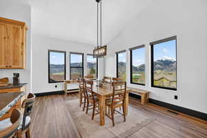 Dining room with lofted ceiling, dark wood-type flooring, suspended lighting, and a mountain view