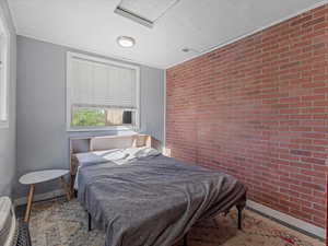 Bedroom featuring brick wall, an accent wall, and ornamental molding