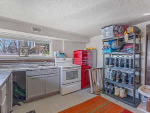 Kitchen featuring white range with electric stovetop, gray cabinets, light countertops, a textured ceiling, and finished concrete floors