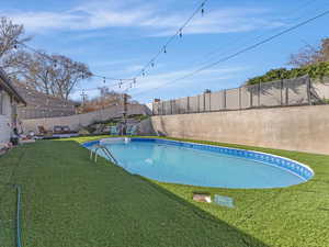 View of swimming pool featuring patio surround and a fenced backyard