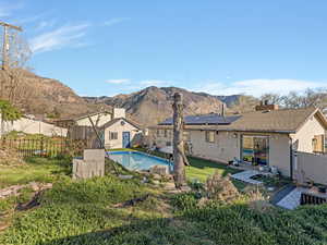 Back of property featuring a patio area, a fenced backyard, roof mounted solar panels, and a mountain view