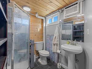 Bathroom featuring wooden ceiling, wooden walls, a shower stall, and dark tile patterned floors