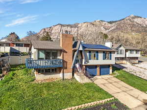 View of front of home featuring roof mounted solar panels, a chimney, driveway, and a garage
