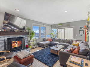 Living room featuring a fireplace, wood finished floors, recessed lighting, and a textured ceiling