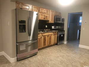 Kitchen with stainless steel appliances, dark stone counters, and backsplash
