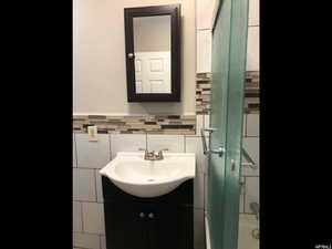 Bathroom featuring vanity, tile walls, and enclosed tub / shower combo