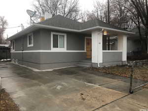 View of front of property with stucco siding, a shingled roof, and a chimney