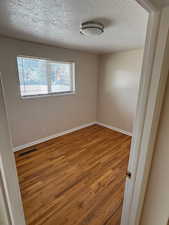 Unfurnished room featuring wood-type flooring and a textured ceiling