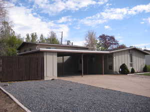 View of front of house featuring board and batten siding, a carport, driveway, and brick siding
