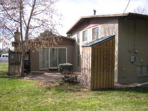 Rear view of house featuring a lawn, brick siding, a patio area, and a shed