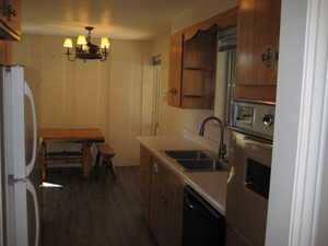 Kitchen with light countertops, freestanding refrigerator, open shelves, wood finish cabinets, and dishwasher