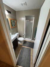 Bathroom with vanity, a stall shower, a textured ceiling, and light tile patterned floors