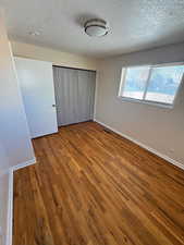 Unfurnished bedroom featuring wood finished floors and a textured ceiling