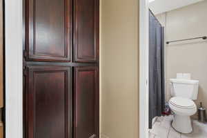 Full bath with curtained shower and light tile patterned floors