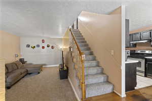 Stairway featuring a textured ceiling and baseboards
