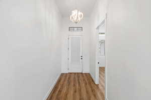 Doorway to outside with a chandelier and wood finished floors