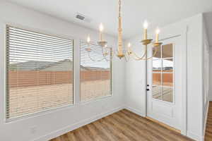 Unfurnished dining area featuring light wood-style floors and suspended lighting