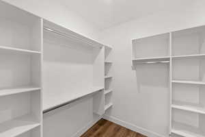Walk in closet with dark wood finished floors