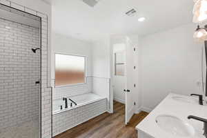 Bathroom featuring dark wood finished floors, a garden tub, walk in shower, double vanity, and recessed lighting