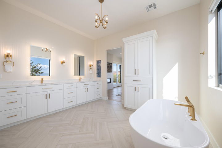 Full bathroom with double vanity, a freestanding bath, a chandelier, and parquet flooring