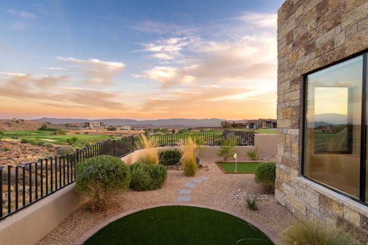 Yard at dusk featuring a fenced backyard, an area to practice putting, and a mountain view