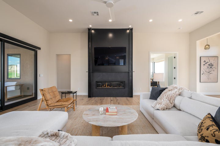 Living room with light wood finished floors, a large fireplace, and recessed lighting