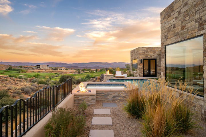 Pool at dusk with an in-ground hot tub, a patio area, and a mountain view