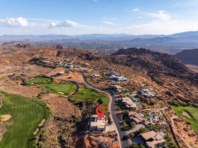 Aerial perspective of suburban area featuring a golf course and a mountainous background