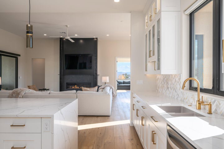 Kitchen featuring white cabinets, open floor plan, light stone countertops, glass fronted cabinets, and light wood finished floors